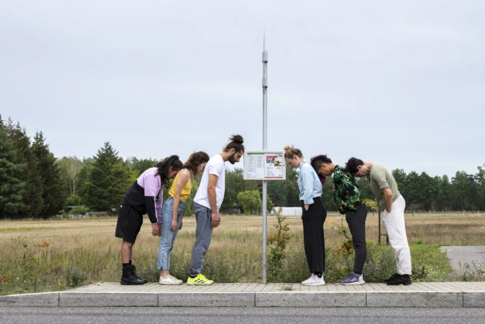 Personen lehnen an einer Bushaltestelle als Performance