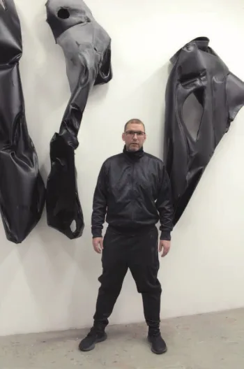 Der Künstler steht vor einem Kunstwerk in einer Galerie.
