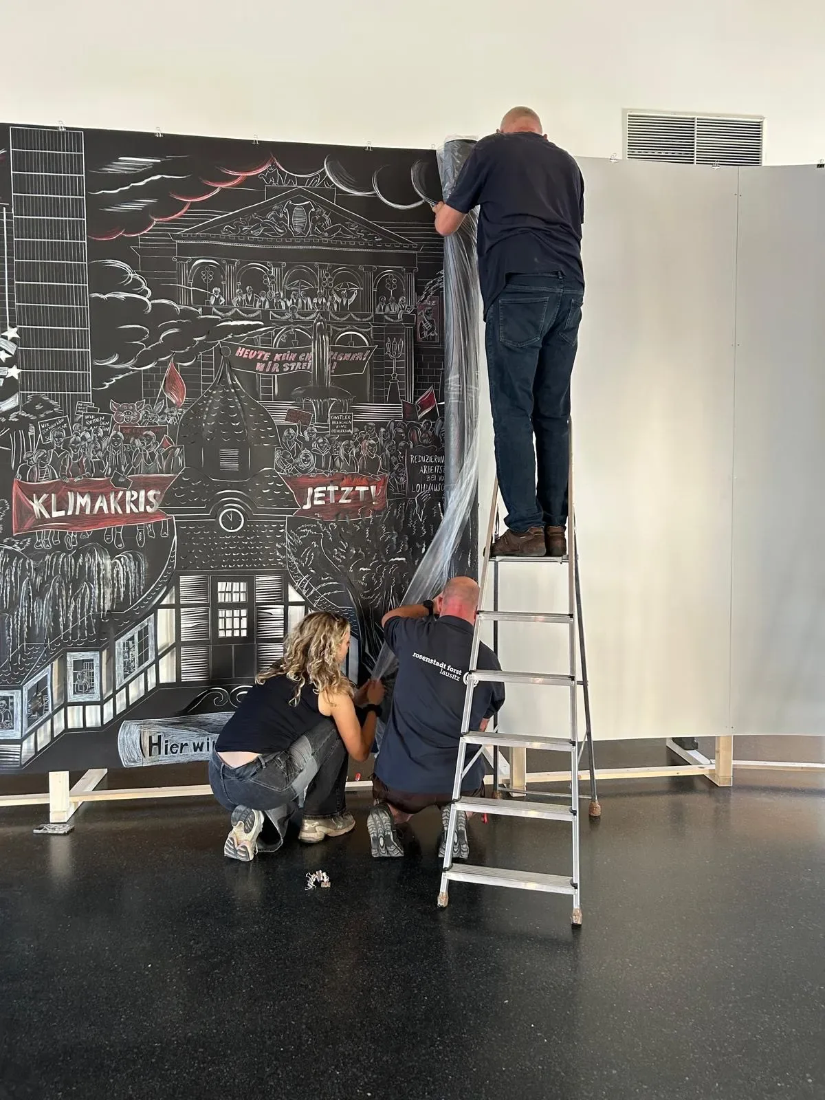 
              Team setting up the exhibition in front of "State of Strike", Sonja Yakovleva, 2024              