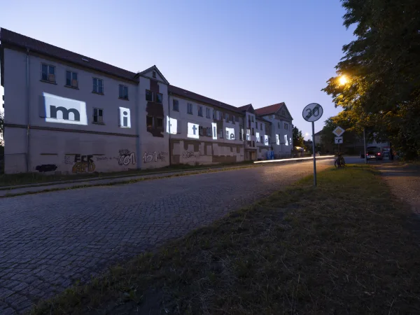 angestrahltes Wort "mittlerweile" auf einer Hausfassade